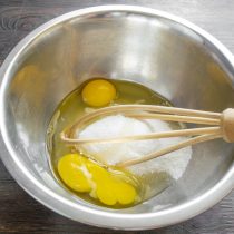 Разбиваем в чашу куриные яйца, насыпаем мелкий белый сахар-песок.