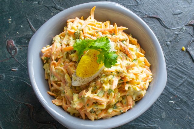 Выкладываем салат из моркови с сыром и яйцом в салатник. Украшаем вареным яйцом, листиком петрушки, посыпаем молотым черным перцем.