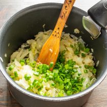 Зеленый лук нарезаем мелко, бросаем нарезанный лук в тушеную капусту. Зеленый лук нарезаем мелко, бросаем нарезанный лук в тушеную капусту.