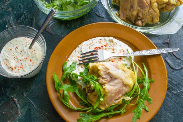 Выкладываем на тарелку несколько ложек густого соуса дзадзики. Рядом кладём кусочек холодной курицы, кожу с курицы лучше снять. Добавляем горсть руколы.