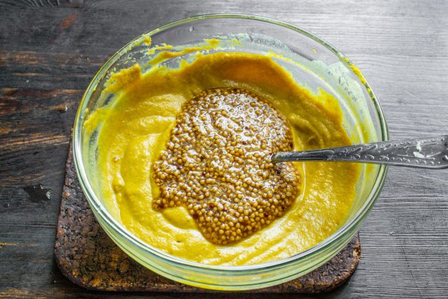 Добавляем в гладкую основу текстурный ингредиент. Выкладываем готовую зернистую горчицу в заваренную массу для создания правильной структуры соуса.