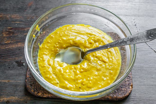 Завершаем приготовление эмульсии добавлением жиров. Вливаем рапсовое масло без запаха в горчичную пасту и еще раз интенсивно всё перемешиваем ложкой.