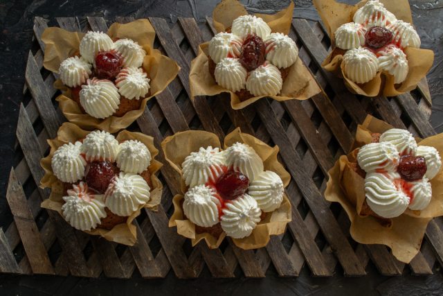 Финальный штрих: в центр кремовой шапочки помещаем целую ягоду клубники и добавляем каплю сиропа.