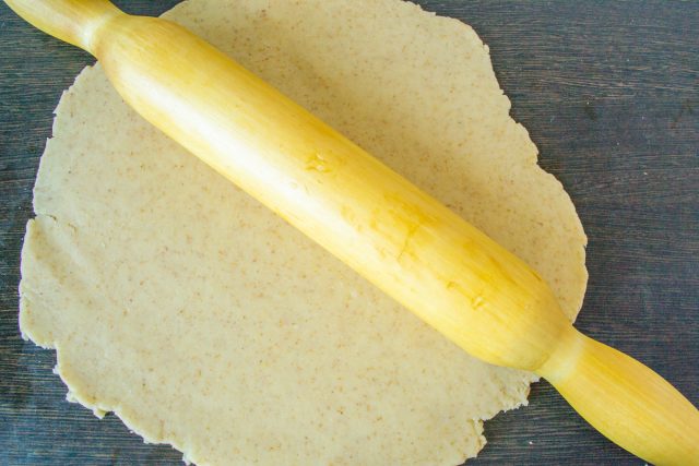 Посыпаем стол мукой и раскатываем отдохнувшее тесто в тонкий пласт. Делаем круг чуть больше диаметра сковороды, чтобы полностью накрыть всю начинку.