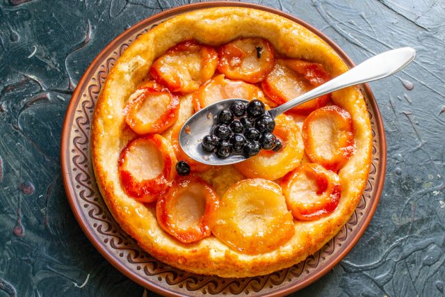 Высыпаем голубику в сковороду, добавляем вино, сахар и прогреваем. Выкладываем ягоды на груши, чтобы пропитать пирог ароматным соусом перед подачей.