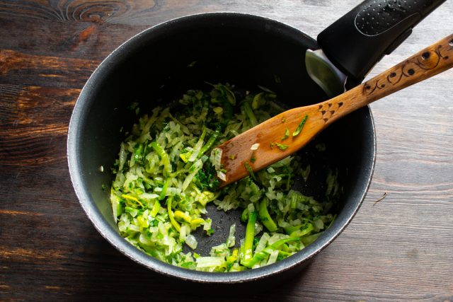 Мелко рубим свежую петрушку и добавляем к луку. Обжариваем овощи с зеленью на умеренном огне около 5 минут, помешивая, пока лук не станет мягким и прозрачным.