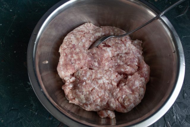 Выкладываем в глубокую миску охлажденный свиной фарш с содержанием жира около 30%.