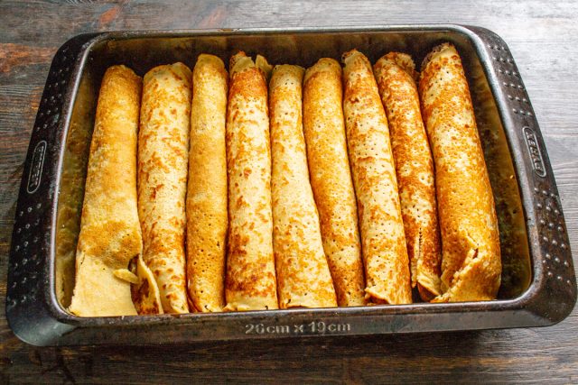 Формируем остальные блины с мясной начинкой и плотно укладываем их в форму рядами. Количество изделий зависит от диаметра сковороды и толщины теста.