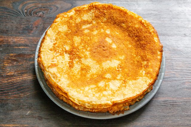 Жарим тонкие блинчики на раскаленной сковороде с двух сторон до румяности. Складываем готовые изделия стопкой на тарелку, не смазывая их дополнительно.