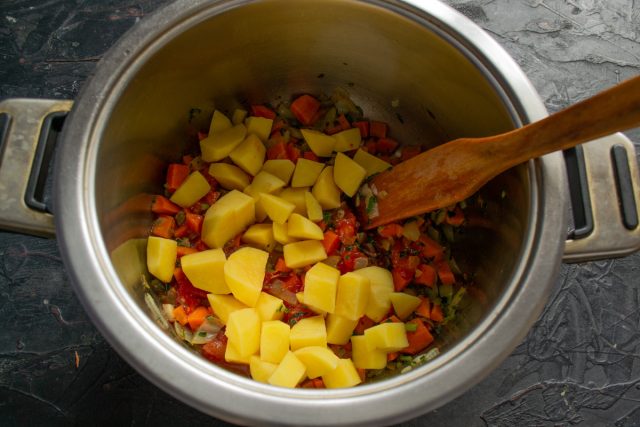 Очищаем клубни картофеля от кожуры и нарезаем их крупными одинаковыми кубиками. Перекладываем картофельную нарезку в кастрюлю к томатной зажарке.