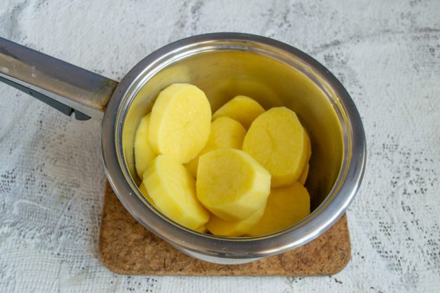 Очищаем картофель от кожуры, нарезаем клубни крупными ломтиками. Добавляем к нарезке зубчик чеснока, предварительно измельченный тонкими пластинками.