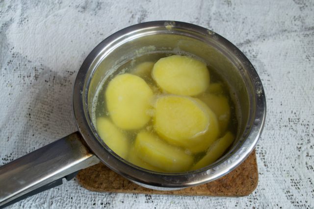 Заливаем подготовленный картофель с чесноком кипятком в кастрюле. Варим овощи на умеренном огне до полной мягкости, не допуская сильного разваривания.