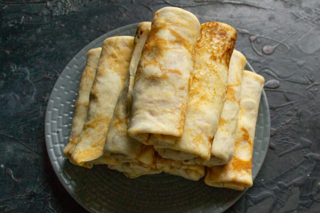 Сворачиваем края блина к центру плотным конвертом, надежно упаковывая начинку внутри. Формируем таким образом все заготовки из теста и мяса.