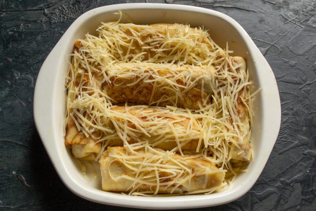 Выкладываем блины в смазанную маслом форму. Посыпаем тертым сыром и вливаем полстакана бульона, чтобы блюдо получилось сочным и мягким внутри.