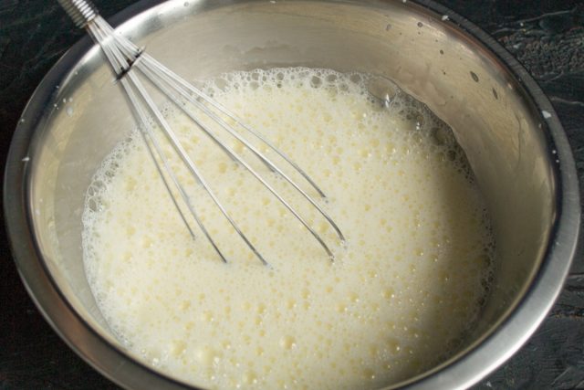 Вливаем к взбитым яйцам холодное молоко и снова тщательно перемешиваем. Жидкость можно разбавить водой или использовать сыворотку для легкости.