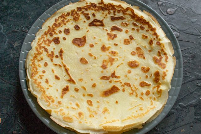 Жарим тонкие блины на разогретой сковороде с двух сторон до золотистого цвета. Складываем готовые изделия стопкой, промазывая сливочным маслом.