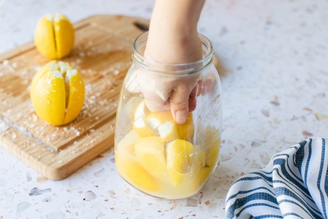 Солёные лимоны — это не десертная заготовка, а мощная кулинарная приправа: за месяц кожура становится мягкой, вкус — сложным и солоновато-цитрусовым. Её мелко режут и добавляют в тушёную курицу, рыбу, салаты или хумус, где она работает как яркий ароматный акцент.