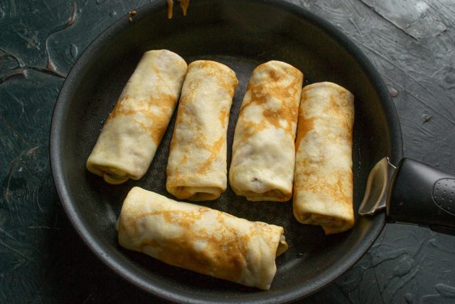 Растапливаем на сковороде кусочек сливочного масла и выкладываем блины. Обжариваем их до хрустящей корочки, чтобы прогреть начинку и улучшить вкус теста.