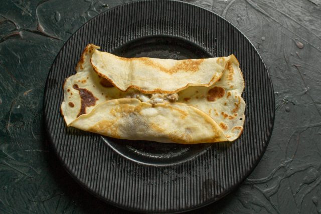 Загибаем края блина на начинку с двух противоположных сторон, фиксируя мясо и яйца. Это предотвратит выпадание начинки при последующей обжарке и еде.