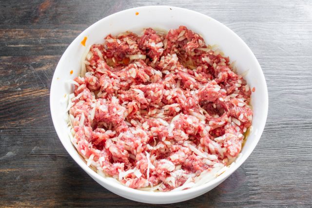 Распределяем фарш с рисом поверх капустного слоя. Выкладываем мясо рыхло, не утрамбовывая, чтобы сквозь него свободно циркулировали овощные соки и заливка.