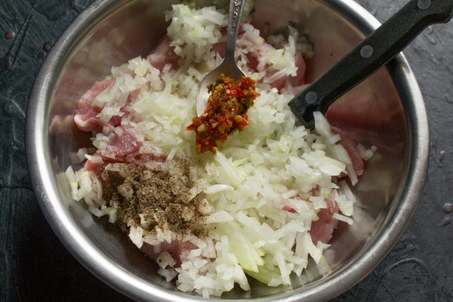 Добавление острой аджики и специй к кусочкам мяса