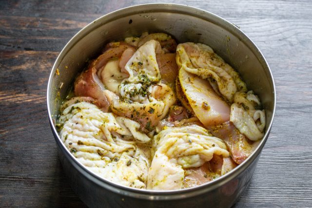 Срезание мяса с кости куриного бедра ножом и маринование кусочков в масле со специями