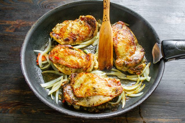 Добавление нарезанного перьями лука на сковороду к жарящейся курице
