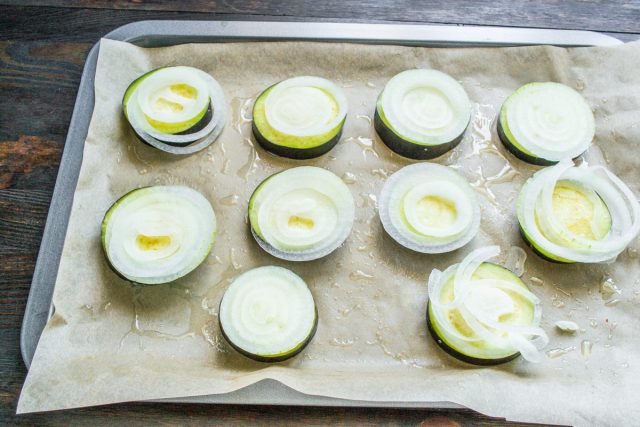 Нарезаем репчатый лук очень тонкими аккуратными колечками и аккуратно выкладываем их сверху на кружочки баклажанов, равномерно распределяя по всей поверхности. Нарезаем репчатый лук очень тонкими аккуратными колечками и аккуратно выкладываем их сверху на кружочки баклажанов, равномерно распределяя по всей поверхности.